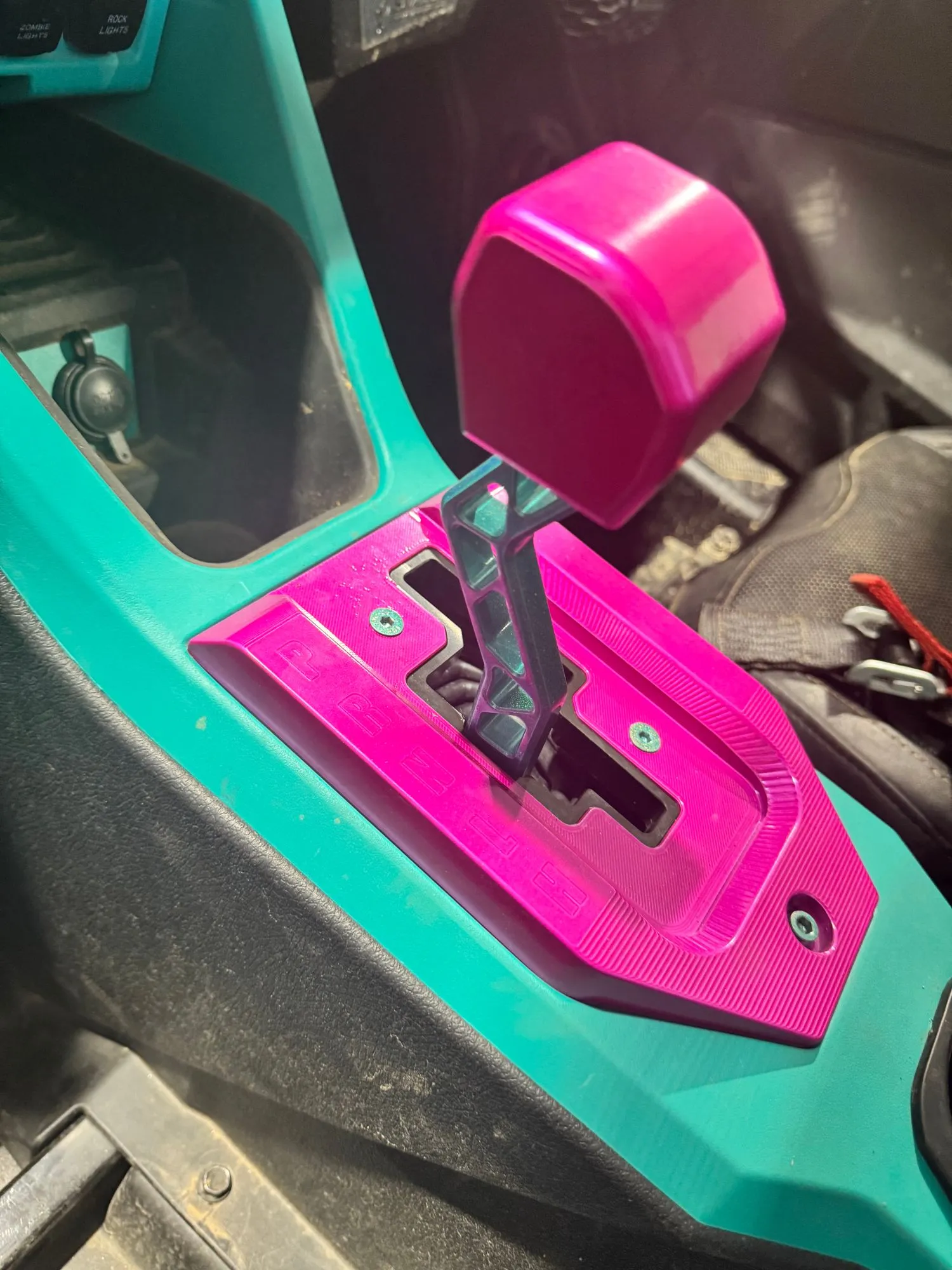 Pink powder-coated shifter plate and knob installed in a UTV with a teal console