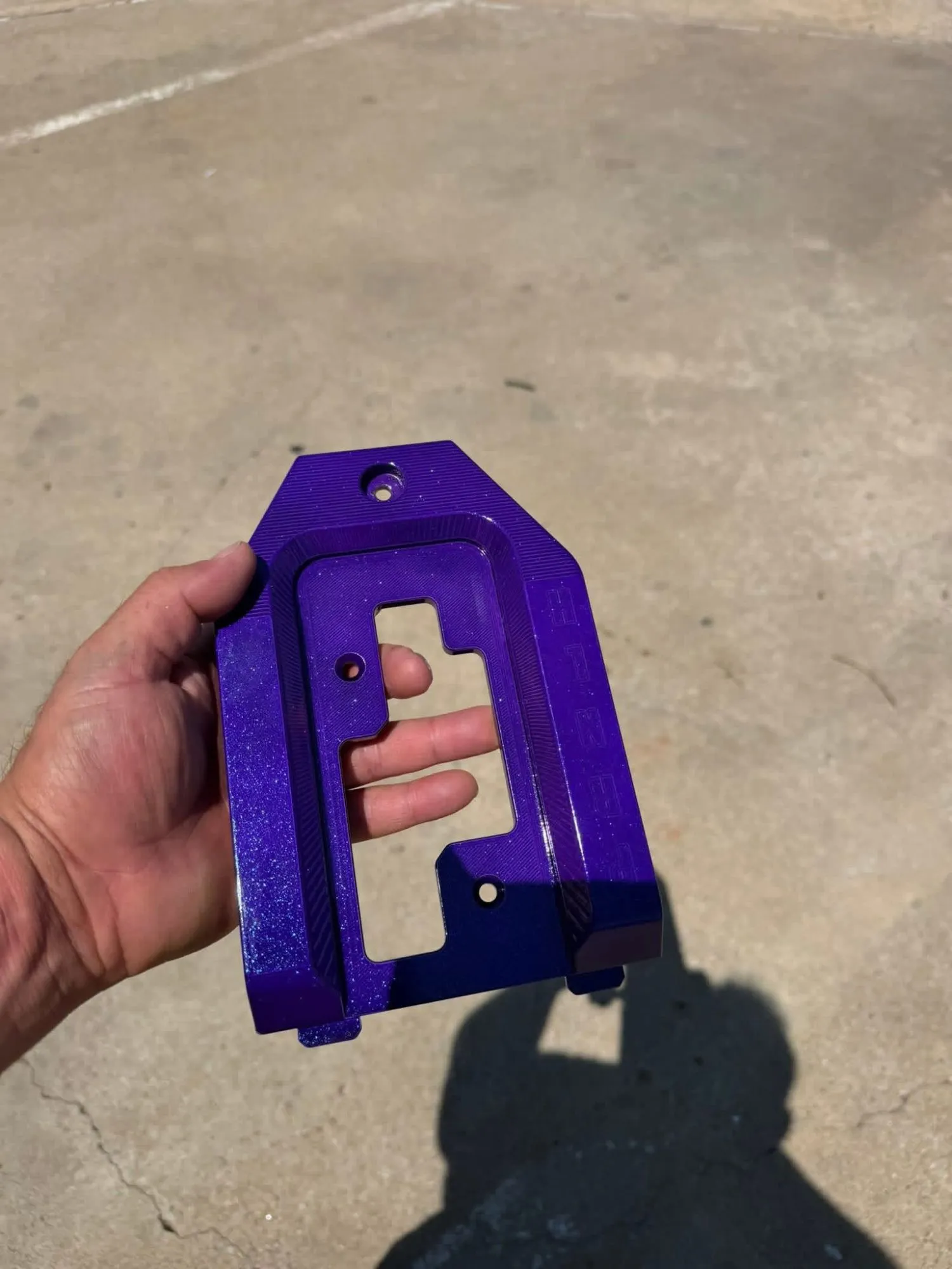 Purple metal-flake powder-coated shifter plate held up in the sun